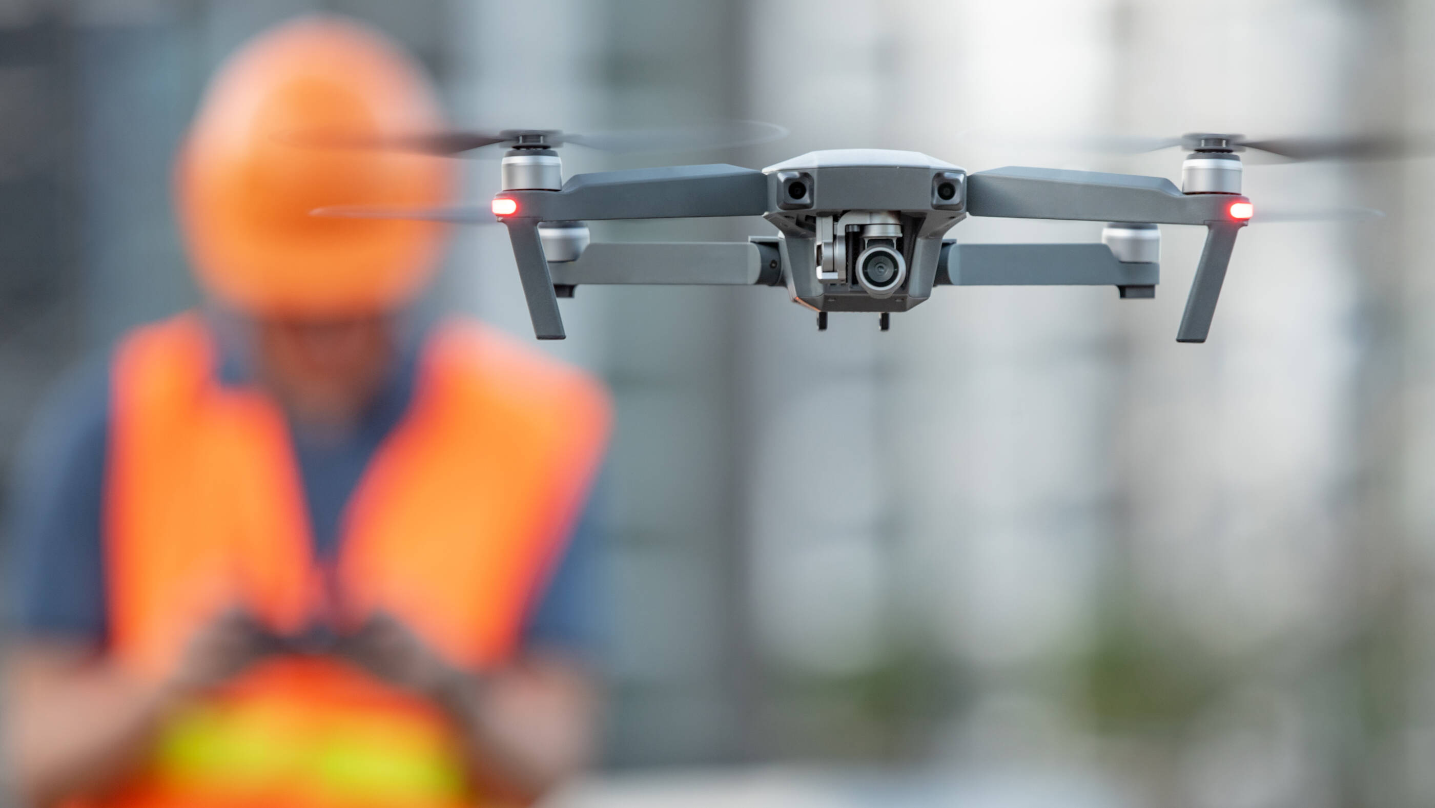 operator of drone in safety equipment flying drone in the foreground