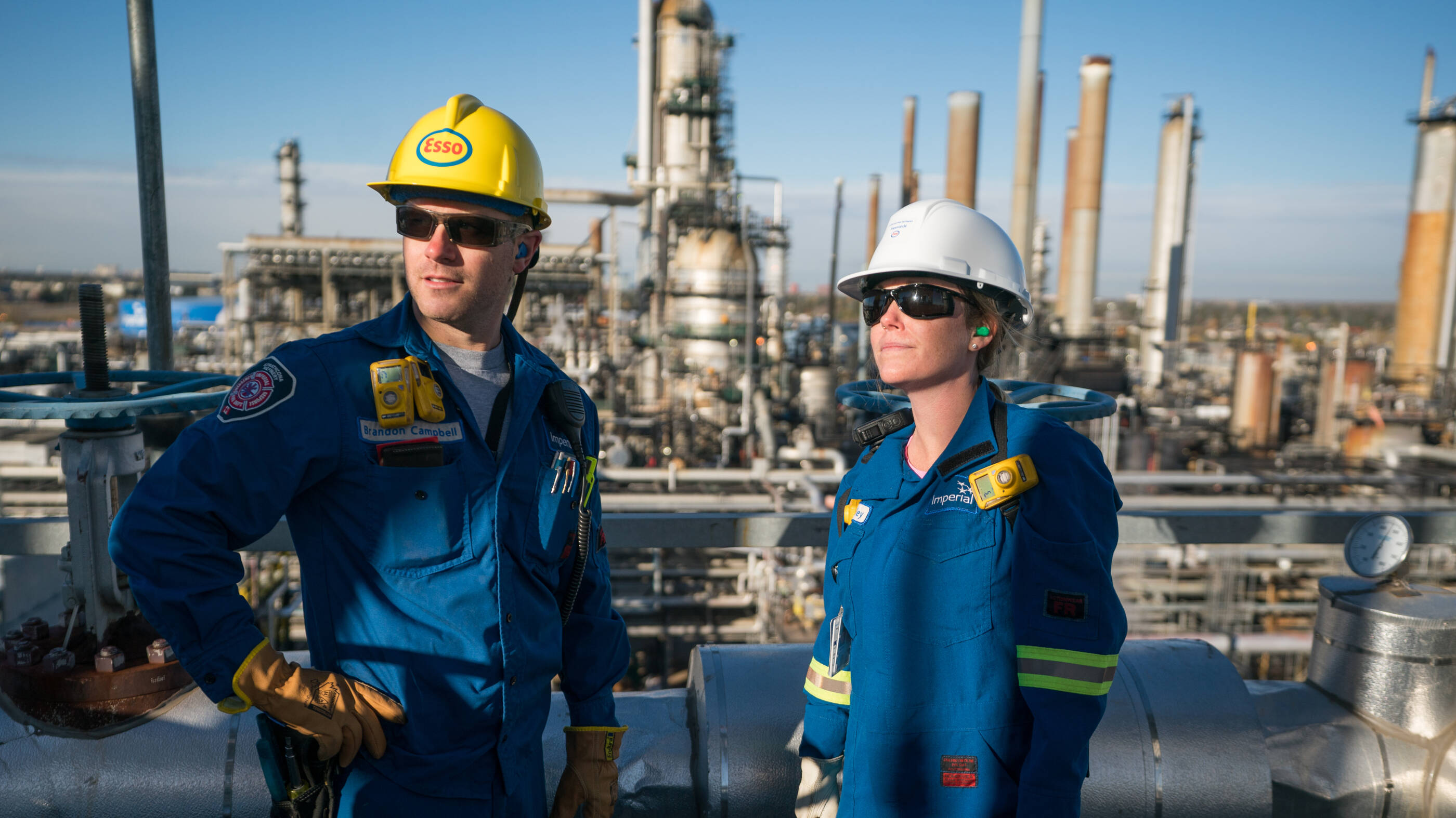 employees in safety gear surveying refinery operations