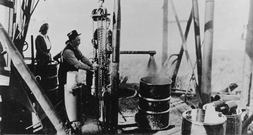 Charles Taylor, manager of Producing Department for Imperial Oil, turning on oil gusher at Norman Wells, Northwest Territories